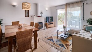 A modern living room with a dining area, a fireplace, a TV, and a large sliding glass door to the outdoors. - Nice holiday house with pool and sea view (Porches)