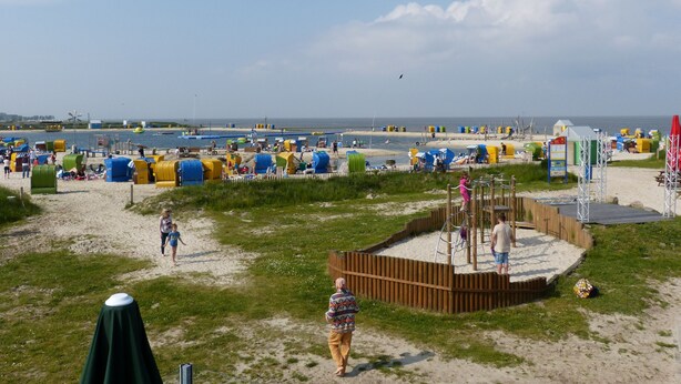 A beach with colorful beach huts and a playground area. - The family-friendly Villa Linus is located in a vacation park behind the dyke (Butjadingen)