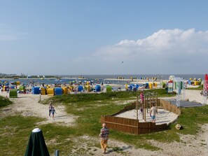Una playa con cabañas de colores y una zona de juegos.