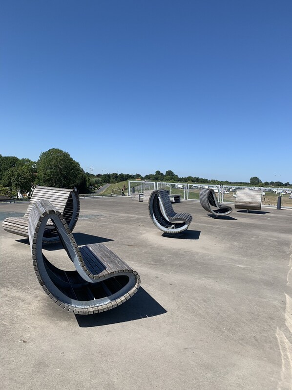 Zonas de estar al aire libre con un diseño moderno, rodeadas de cielo despejado y vegetación.
