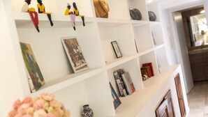 Una estantería blanca con varios objetos decorativos, como un florero, marcos con fotografías y pequeñas figuras.