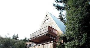 A wooden chalet with a triangular roof and a balcony with intricate railing.