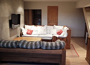 Un salon chaleureux avec un canapé en bois, une petite table en bois et un tapis moelleux.
