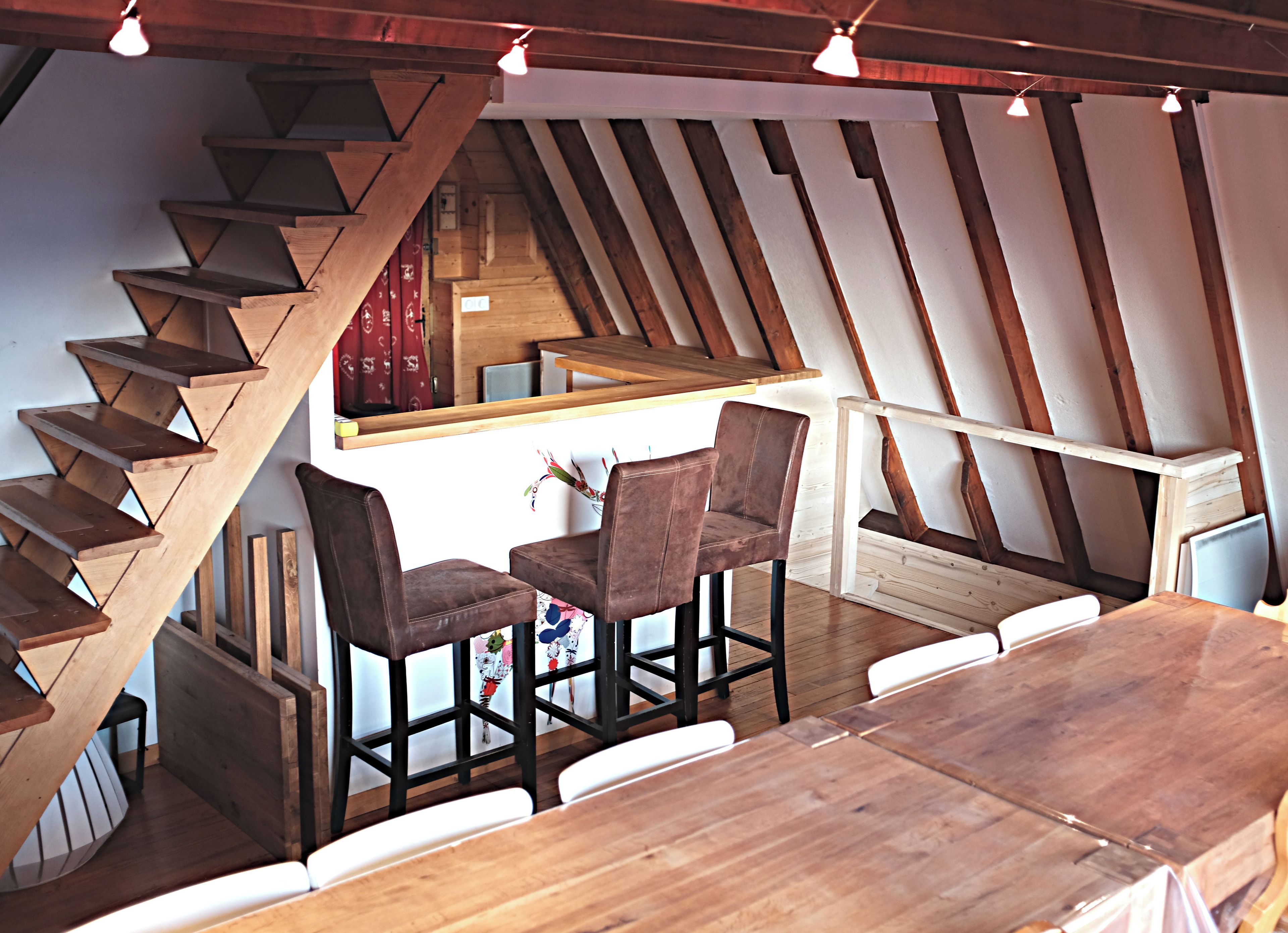 A wooden staircase leading to a dining area with a table and chairs.
