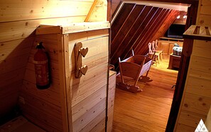 Cozy cabin interior with a warm, rustic ambiance, featuring a wooden door, fire extinguisher, and small wooden cart.