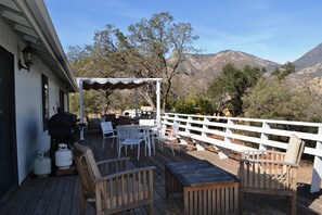 Un patio al aire libre con muebles de madera, una pérgola y vistas a las montañas.