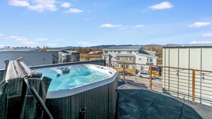 A hot tub on a balcony with a view of buildings and a body of water in the background. - Downtown Mountain Views Craftsman Stunner 5 bd/4b (Fort Collins)