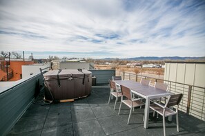 An outdoor patio with a hot tub, a table, and chairs. - Downtown Mountain Views Craftsman Stunner 5 bd/4b (Fort Collins)