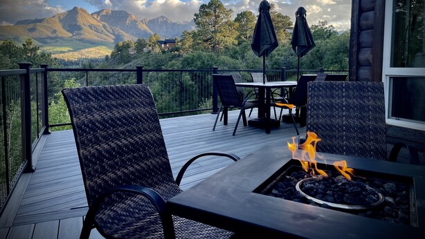 Una terraza con mobiliario exterior, una chimenea y una vista panorámica de la montaña.