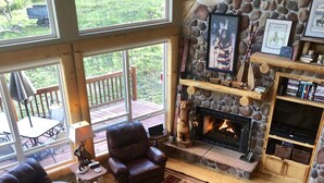 Una sala de estar acogedora con chimenea de piedra, sofás de cuero y una alfombra grande.