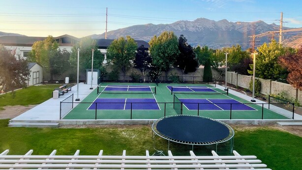 A tennis court with a trampoline and a view of mountains.