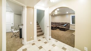A spacious living area with a brown leather couch, a small table, and a chair. A staircase leads to an upper level.