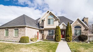 A two-story house with a brick facade, a gabled roof, and a front entrance with a red door.