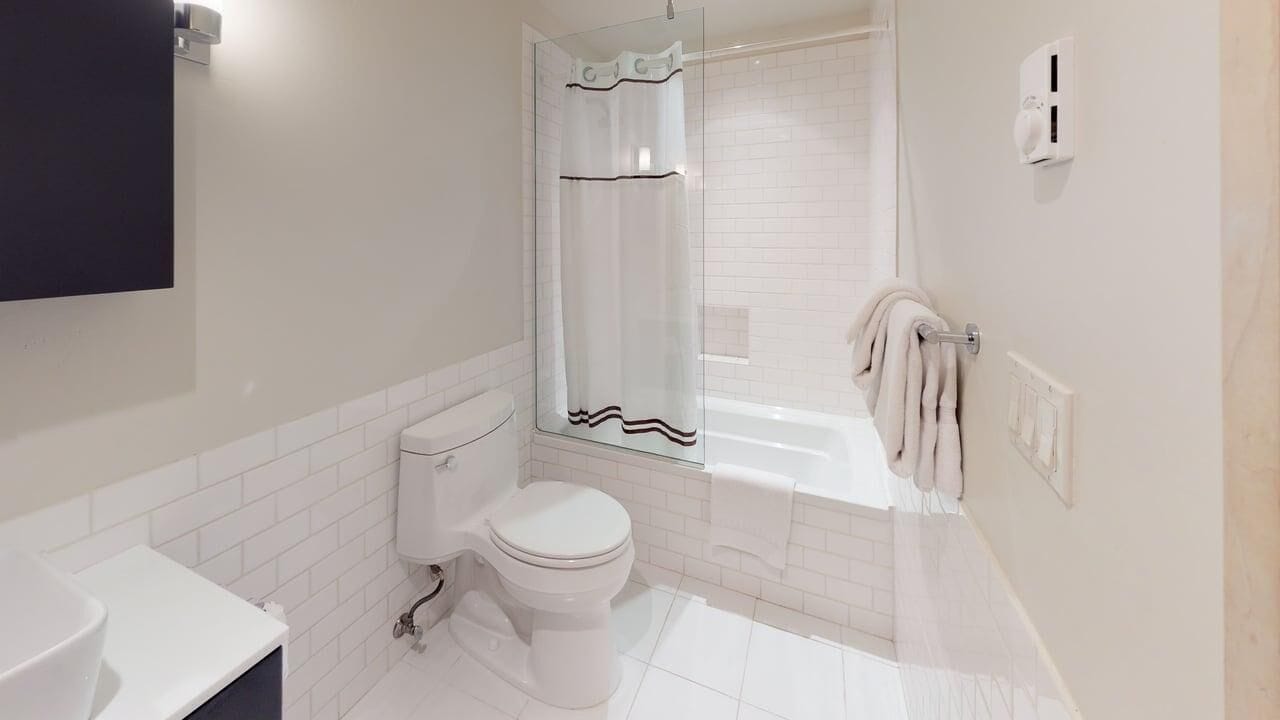 A modern bathroom with a toilet, sink, and glass-enclosed shower.