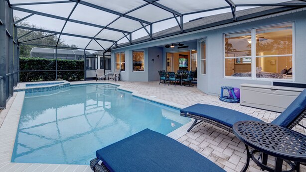 Ein Poolbereich mit Überdachung, Liegestühlen, einem Tisch und einer Terrasse mit Blick auf das Haus.
