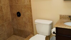 A bathroom with a shower, toilet, sink, and towel rack.