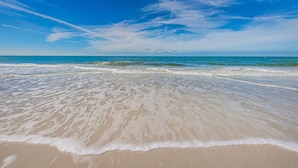 Een strand met heldere lucht en rustige golven.