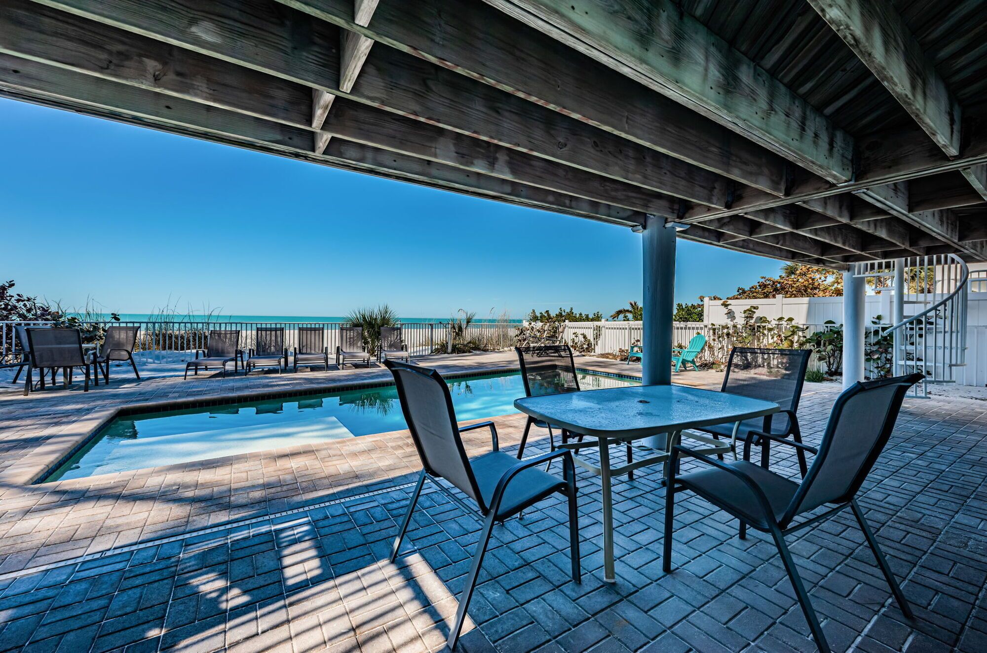 A covered outdoor area with a pool, chairs, and a table.