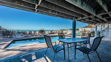 A covered outdoor area with a pool, chairs, and a table.