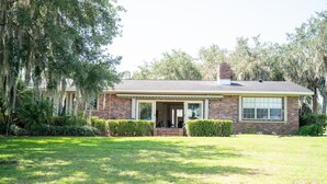 A single-story brick house with a front porch, a chimney, and a well-maintained lawn. - Large beautiful house on lake. Dock, Water trampoline, Fire Pit, Rope Swing, 4/3 (Lake Placid)