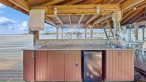 An outdoor kitchen area with a wooden structure, a sink, and a refrigerator. - Large beautiful house on lake. Dock, Water trampoline, Fire Pit, Rope Swing, 4/3 (Lake Placid)