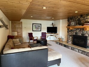 A cozy living room with a stone fireplace, a television, and comfortable seating.