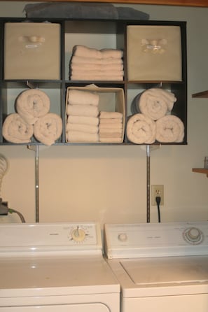 Convenient laundry facilities feature two front-loading washing machines and a shelf for folded towels and linens.