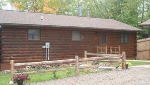 A log cabin with a wooden deck and a gravel driveway. - Bears Den on the private lake (Winter)