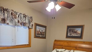 A bedroom with a wooden bed, a ceiling fan, and two framed pictures on the wall. - Bears Den on the private lake (Winter)