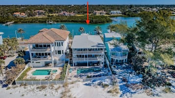 A beachfront property with a large house, a pool, and a view of the ocean.