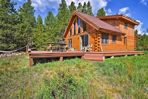Situated on a raised platform, this cabin offers a clear view of the surrounding forest from its multiple windows and a spacious deck with outdoor seating.