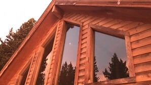 Una cabaña de madera con ventanas amplias y techo inclinado.