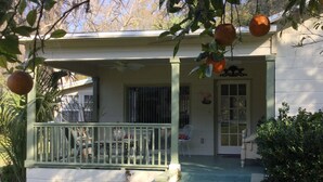 A house with a porch, steps leading to a door, and a small garden area. - Orange Blossom in Historic McIntosh (McIntosh)
