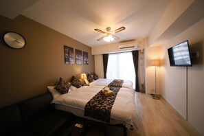 A hotel room with a bed, a ceiling fan, an air conditioning unit, a television, and a clock on the wall. - Best Residence Kujo 502 (Osaka)