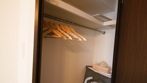 Un piccolo armadio compatto con un aspirapolvere e ripiani con vestiti piegati.