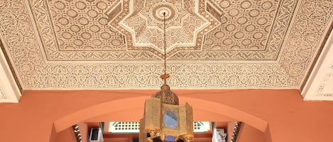 Teto detalhado com padrões geométricos complexos e um candelabro pendurado.