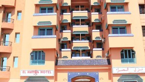 A multi-story hotel with balconies, a sign reading "El Hamad Hotel," and a parked car in front. - El Hamra Hotel (Marrakech)