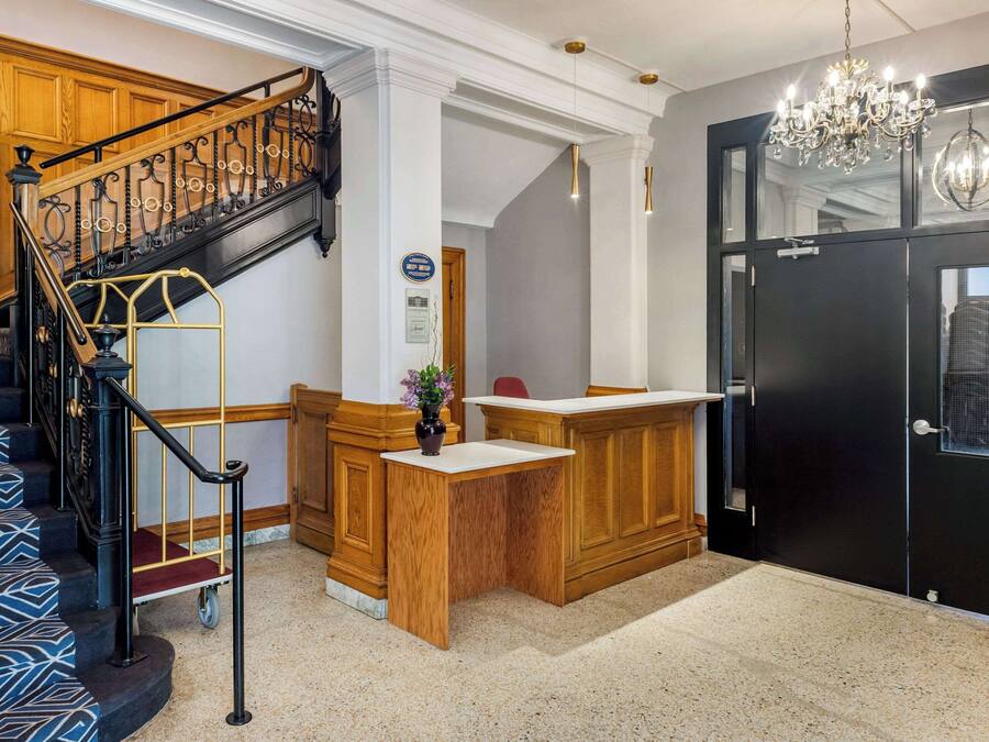 A reception area with a wooden desk, a black door, and a staircase with patterned steps.