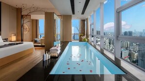 A modern hotel room with a large window, a long swimming pool, and a city view. - Ramada by Wyndham Changsha Downtown (Changsha)
