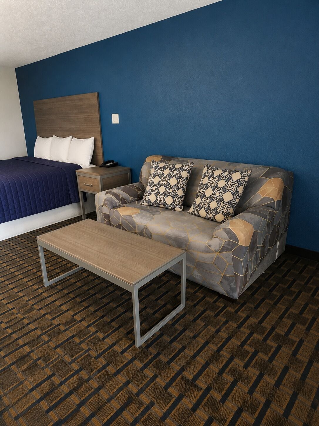 Een hotelkamer met een bed, een slaapbank, een nachtkastje en een salontafel.