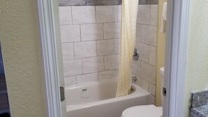 Ein Badezimmer mit Dusche, Toilette und Fliesen.