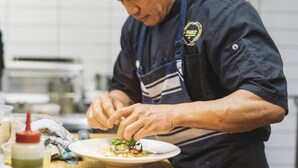 A person in a chef's uniform preparing food in a kitchen. - Bond Street Apartment Luxury 3-bedroom (Dunedin)