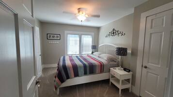 A bedroom with a bed, nightstands, a ceiling fan, and a door.