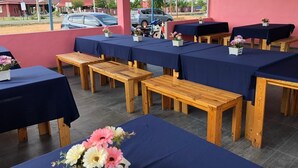 Un espacio de estar al aire libre cubierto con mesas y bancos, algunos adornados con flores.