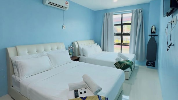 Habitación de hotel con dos camas, televisión, aire acondicionado y ventana con cortinas.