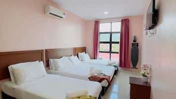 A hotel room with two beds, a TV, a window with curtains, and an air conditioning unit.