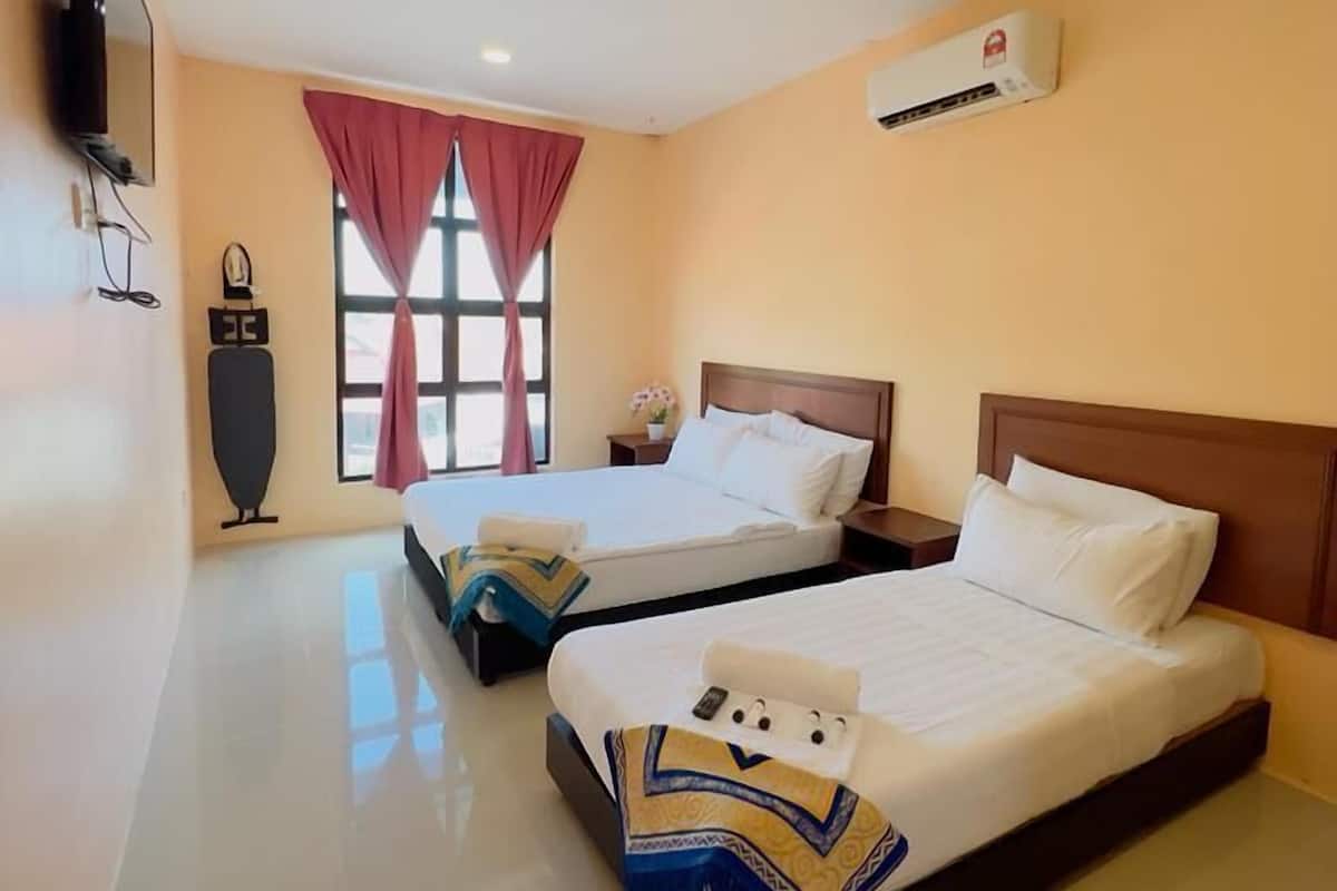 Una habitación de hotel con dos camas, un televisor de pantalla plana, aire acondicionado y una ventana con cortinas.