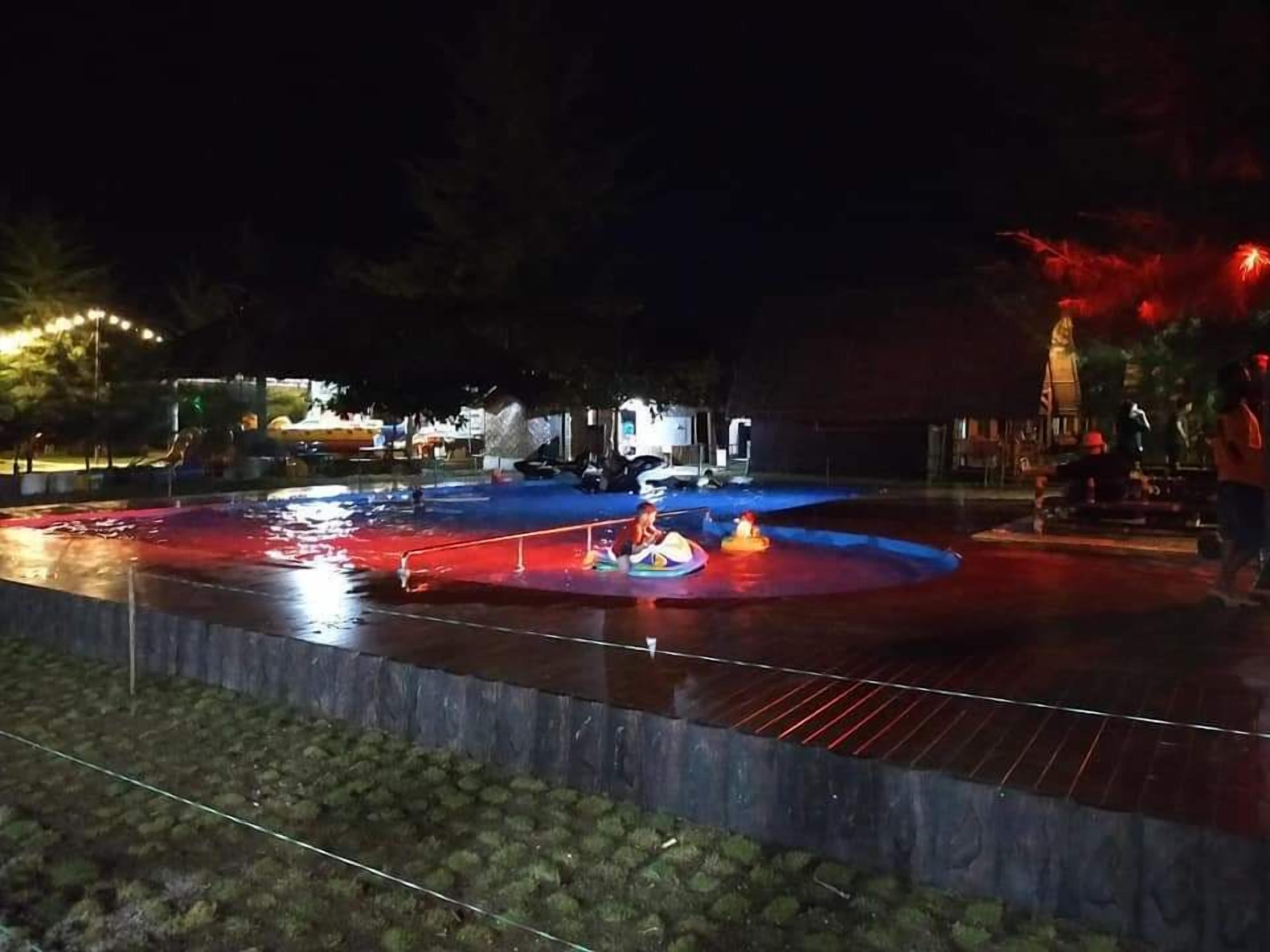 An outdoor pool area with a wooden deck and a metal railing.