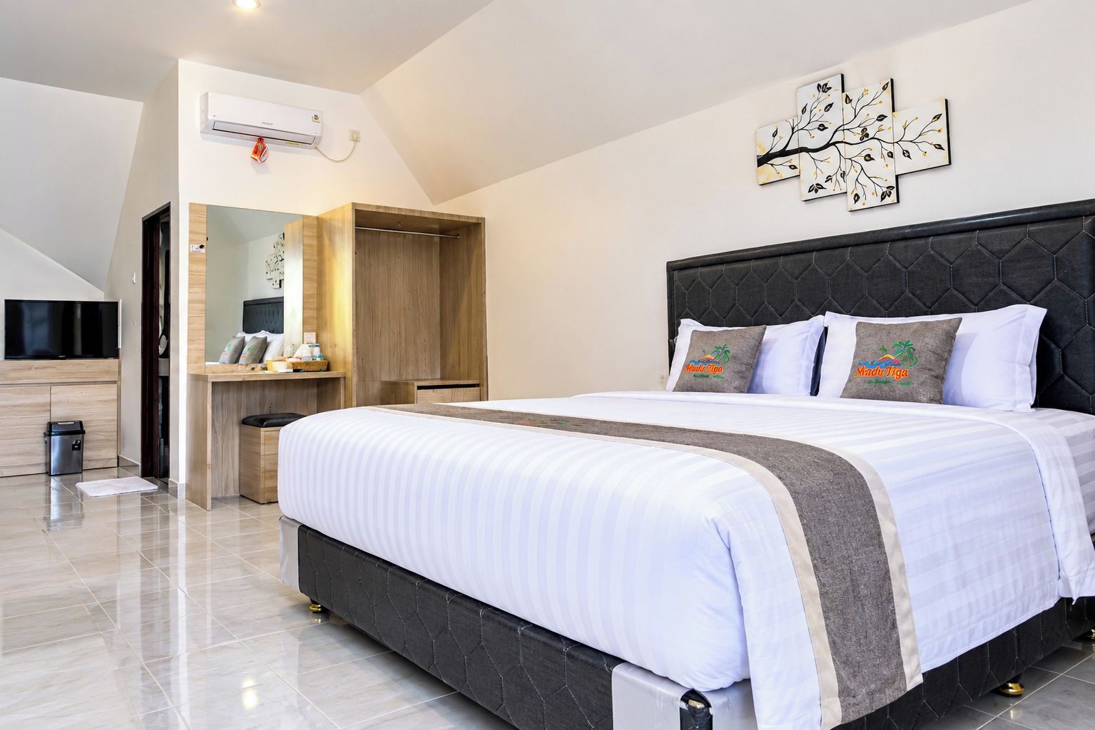 Habitación de hotel moderna con una cama grande, un televisor de pantalla plana, un armario y un aire acondicionado de pared.