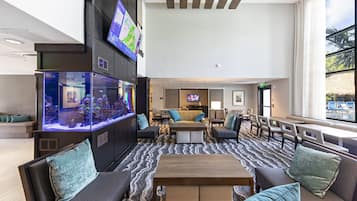 A spacious lobby with a large aquarium, comfortable seating, a television, and a view of the outdoors.